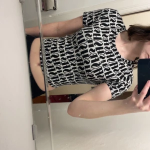 Svartvit topp med snörning från FB Sister - Trendig svartvit topp från FB Sister med grafiskt mönster och snörningsdetaljer på ryggen. Kortärmad och tight passform, perfekt för att sticka ut. Snygg och unik design med korsade band längs sidan.