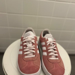 Adidas rosa sneakers - Säljer ett par snygga Adidas sneakers i rosa mocka med vita detaljer på sidorna💗