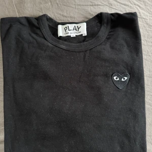 Svart långärmad tröja från Comme des Garçons Play - Säljer en svart långärmad tröja från Comme des Garçons Play med det ikoniska hjärta-loggan på bröstet. Tröjan har rund halsringning och är i mjuk bomull. Perfekt för en stilren och enkel look.