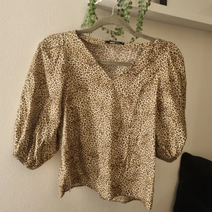 Leopardmönstrad blus från Gina Tricot - Säljer en snygg leopardmönstrad blus från Gina Tricot med v-ringning och puffiga trekvartsärmar. 