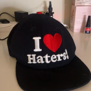 Svart keps från DGK x Hayo med broderad text - Snygg 2010s keps med vit broderad text 'I heart Haters!' framtill och 'Motivation' under skärmen. Justerbar snapback och i bra skick! Aldrig använd bara testad, köpt på vinted 💕