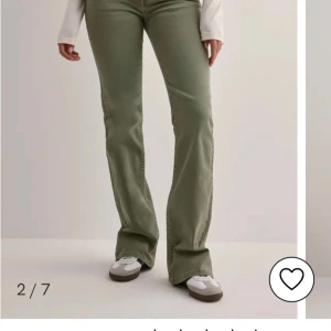 Gröna nelly bootcut jeans - Säljer ett par olivgröna bootcut jeans med snygga broderade detaljer på bakfickorna. Jeansen har normal passform och är tillverkade i ett mjukt bomullsmaterial. Perfekta för dig som gillar en avslappnad men trendig stil.