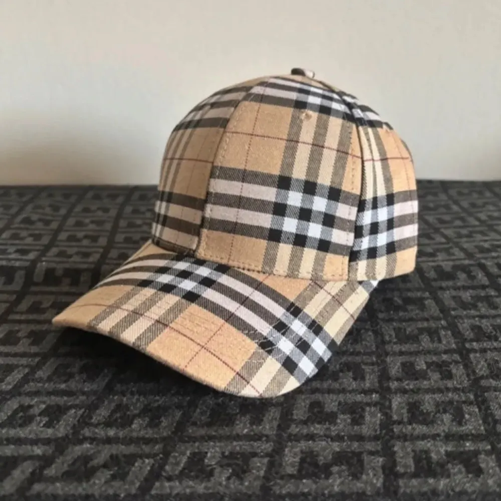 Snygg keps från Burberry i klassiskt beige rutigt mönster med svarta och vita detaljer. Justerbart spänne baktill i metall och broderad Burberry-logga på insidan. Perfekt accessoar för en trendig look. Kepsen är inte äkta!!!. Asusteet.