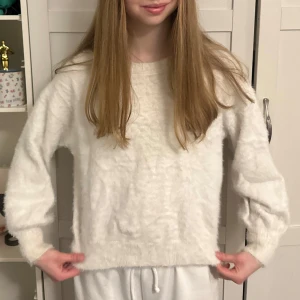 Vit fluffig tröja från New Look - Supermjuk och fluffig vit tröja från New Look. Tröjan har lång ärm och en enkel, rak passform. Perfekt för dig som gillar en mysig och stilren look. Passar till många olika outfits!