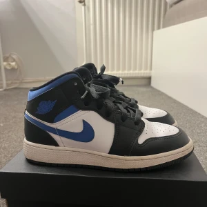 Air Jordans Mid - Säljer ett par Air Jordans i svart, blått och vitt. Skorna har klassisk hög modell med svart snörning. Jag har bara använt skorna några fåtal gånger och jag har även kartongen till dem kvar.  Skorna har inga större defekter, det ända är att dem är lite creasade som man ser på bilderna men annars är dem jätte fräscha:)