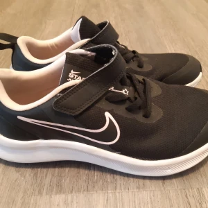 Svart/rosa Nike sneakers i mkt fint skick! - Säljer ett par svart/rosa Nike sneakers i mycket fint skick. Använd ett fåtal gånger bara. Skorna har både snörning och kardborreband för extra bra passform. Ovandelen är i mesh-liknande syntetmaterial och insidan är ljusrosa. Perfekta för träning eller vardag.