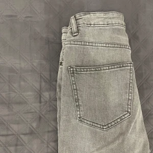 Grå jeans - Använda endast 1gång. Byxorna har normal passform med en flare och en liten slit. Perfekta till många olika outfits och enkla att matcha.