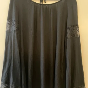 Svart blus med spetsdetaljer - Säljer en svart blus i storlek L, med vida ärmar och vackra spetsdetaljer både vid ärmslut och överarm. Blusen har rund halsringning med knyt i nacken. Använd nån enstaka gång😊