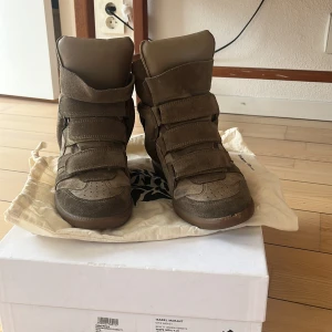 Taupe Beckett sneakers med kilklack från Isabel Marant - Säljer ett par taupe / beige sneakers med kilklack från Isabel Marant. Modellen är Beckett. Äkta och kommer med låda och skopåsar. I bra använt skick förutom en liten rispa/ flik längst fram i sulan. Inget man tänker på när man har på sig dem. Pris 1200 kr