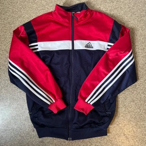 Adidas track jacket - Snygg Adidas track jacket i rött och marinblått med vita detaljer och klassiska ränder på ärmarna. Gott skick💙❤️