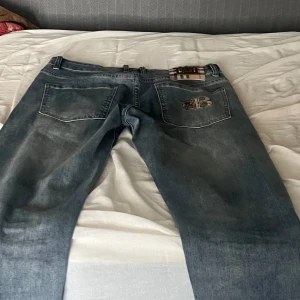Blå jeans med broderad detalj - Snygga blå jeans med raka ben och broderad detalj Klassiska blå jeans i en tidlös femficksmodell med rak passform och normal midja (midwaist). En vacker, broderad detalj på bakfickan ger byxan det lilla extra. Perfekta för en avslappnad vardagsstil – lika snygga med sneakers som med boots. Ett måste i basgarderoben!