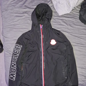 Moncler Windbreaker - Moncler regnjacka i storlek L/M, en stilren jacka som är perfekt för regniga dagar, jackan har 2 dragkedjor och har fina detaljer, påse ingår, använd fåtal gånger och kostar bara 1000kr! Pris går att diskutera