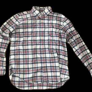 Rutig skjorta från Ralph Lauren - Säljer en klassisk rutig skjorta från Ralph Lauren i vitt, blått och rött. Skjortan har långa ärmar, knappar framtill och broderad logga på bröstet. Perfekt för dig som gillar tidlös stil och vill ha något som sticker ut lite extra.