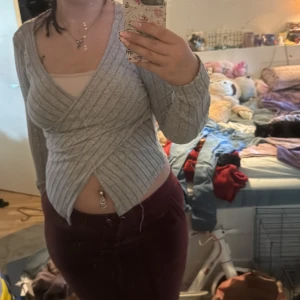 Grå omlottopp från SHEIN - Säljer en grå ribbad omlottopp från SHEIN med lång ärm. Tröjan har en tight passform och omlottdesign framtill, vilket ger en snygg och trendig look. Perfekt att styla med både jeans och kjol.