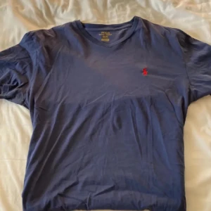 Ralph Lauren T-shirt  - Klassisk Ralph Lauren T-shirt – enkel, stilren och alltid rätt. Tillverkad i mjuk bomull med perfekt passform och den ikoniska broderade ponnyn på bröstet. Passar lika bra till vardags som under en skjorta eller jacka för en mer genomtänkt look. Inga fläckar eller defekter – redo att bäras!