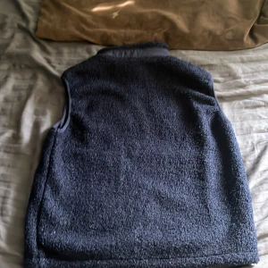 Mörkblå fleeceväst med dragkedja - Mysig mörkblå fleeceväst med dragkedja framtill. Västen har en bröstficka med dragkedja och två sidofickor. 