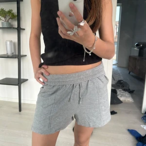 Grå mjukisshorts - Gråa shorts i mjukt material med elastisk midja och snörning. De har en avslappnad passform och två sidofickor. Perfekta för en chill dag på sommaren