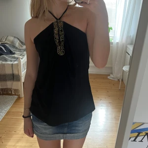 Halterneck topp med paljetter - Halternecklinne som jag korsat banden på, går att ha vanligt också. Storlek S men är rymlig och sitter inte tajt. Öppen rygg och riktigt fina gulddetaljer, någon paljett saknas. Skitsnyggt att ha med svart minikjol!🥰