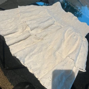Vit volangkjol  - Supersöt vit kjol från Gina Tricot med volanger och broderade blom detaljer. Kjolen har smock i midjan och är kort i modellen, perfekt för varma dagar. Skriv till mig för ytterligare frågor!😊🫶🩷