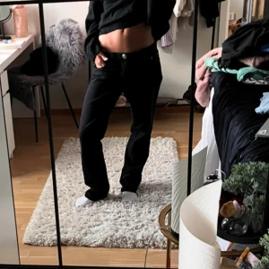 Svarta utsvänga lite baggy jeans med låg midja - Snygga svarta jeans med låg midja och en klassisk bootcut fit. Perfekta för en avslappnad stil. De har knappar och dragkedja framtill.