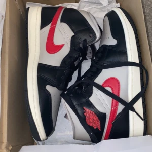 Nike Air Jordan 1 Mid HELT NYA - Säljer ett par Nike Air Jordan 1 Mid SE i färgerna svart, grå och röd. Skorna har klassisk hög siluett, svart snörning och röd swoosh samt Air Jordan-logga på sidan. Perfekta för dig som gillar streetwear och sneakers med attityd. DOM ÄR HELT NYA OCH SÄLJER EFTETSOM DESSA ÄR FÖR SMÅ FÖR MIG OCH HAR REDAN ETT PAR I MIN EGNA STORLEK!! JAG KAN MÖTAS UPP I GBG ELLER SKICKA JAG SKICKAR MER BILDER OM DET BEHÖVS!!!!