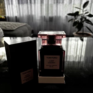 Tom Ford Lost Cherry Eau de Parfum 100 ml - Tom Ford Lost Cherry är en lyxig parfym i en elegant, mörkröd glasflaska med rosa nyanser och vit etikett. Flaskan rymmer 100 ml och har en distinkt fyrkantig form med matchande lock. Förpackningen är stilren och exklusiv, perfekt för dig som gillar unika dofter.