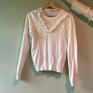 Vit stickad tröja med volang  - Fin vit stickad tröja med volang, stolek L men uppskattas mer till st M-S. Fint skick 