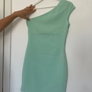 Ljus turkos klänning  - Super fin sommrig klänning från Zara i ljus turkos.  One shoulder och ser exakt likadan ut på baksidan. Storlek M men skulle säga att den är lite liten i storleken så kanske mer mot en S. Kedja på sidan av höften se bild 3. Dragkedjan på sista bilden är lite trög och hoppar typ ut ibland om den är jätte tight men går nog att fixa. Tror ej den finns att köpa någonstans längre.