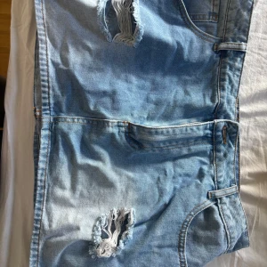 Ljusblå jeanskjol med hål - Säljer en ljusblå jeanskjol med coola slitningar framtill. Aldrig använd. Originellt från shein.