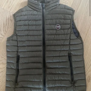 Khaki brown dunväst från colmar  - Snygg olivgrön dunväst från Colmar med quiltad design och dragkedja framtill. Västen har två fickor med dragkedja och en liten logotyp på bröstet. Perfekt för lager-på-lager under kyliga dagar.