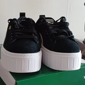 Puma Mayze Wn's sneakers med platåsula - Säljer ett par svarta Puma Mayze Wn's sneakers med vit platåsula och vita detaljer på sidan. Skorna har snörning och en chunky, hög sula som ger extra höjd. Perfekta för dig som gillar streetstyle och vill sticka ut lite extra.                                            Aldrig använda! 