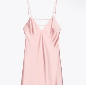 Ljusrosa satinklänning med tunna axelband - Säljer en ljusrosa långklänning i satin med smala axelband och v-ringning. Klänningen har en snygg detalj med extra band över bröstet och öppen rygg. Perfekt för sommarens tillfällen!