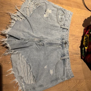 Ljusblå jeansshorts med fransar - Säljer ett par ljusblå jeansshorts med fransiga kanter och slitna detaljer framtill. Lose fit 🥰 