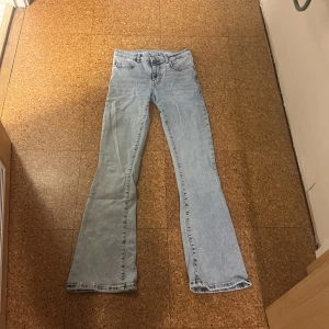 Ljusblå flare jeans från Never Denim - Säljer ett par ljusblå jeans från Never Denim med låg midja och flare-ben. Klassisk femficksmodell i mjuk denim, perfekt för dig som gillar retrovibbar och snygg passform. Snygga till sneakers eller boots.