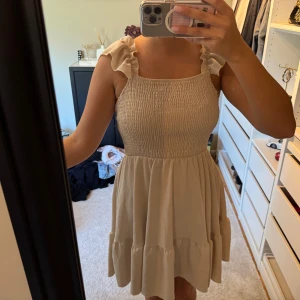 Beige kort volangklänning - Supersöt beige kortklänning med volangiga axelband.