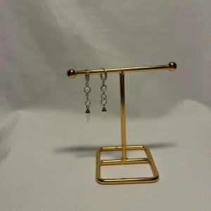 Silvriga örhängen med kedjor och koner - Snygga silvriga örhängen med små ringar och hängande konformade detaljer. Örhängena har en cool kedjedesign och ger en edgy vibe. Perfekta för dig som gillar unika accessoarer med lite attityd.