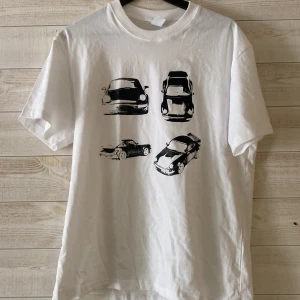 Vit t-shirt med biltryck - Vit t-shirt med svart tryck av en Porsche. Storlek M och är 100% bomull. Jätte skönt och mjukt material