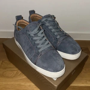 Ljus blåa Louboutin skor - Snygga sneakers i ljus blåa mocka från Louboutin med klassisk röd sula och vita kanter. Skorna har rund tå, snörning och beige innersida i skinn. Perfekta för dig som gillar stilrena och exklusiva detaljer. Storlek 43, använda cirka 2-3 gånger men fortfarande riktigt fin i mockan!