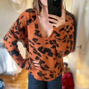 Leopardmönstrad  stickad tröja - Säljer en supermjuk stickad tröja från Inwear i varm brun/orange färg med svart leopardmönster. Tröjan har v-ringad hals, lång ärm och en loose passform. 