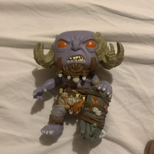 Funko pop - Bilderna visar en fantasy-inspirerad figur med lila hud, stora horn och detaljerade kläder, men ingen bok syns på bilderna.  Har inte låda till den tyvärr 