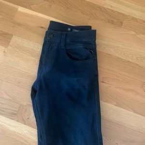 Replay Anbass Hyperflex svarta jeans - Svarta Replay Anbass Hyperflex jeans med slim fit och klassisk femficksdesign. Jeansen är stretchiga och sitter snyggt med normal midja. Perfekta för dig som gillar en stilren look med bekväm passform. Inte alls andvända mycket och de är i bra skick, 