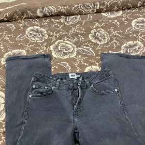 Mörkgrå bootcut jeans från 157 - Snygga mörkgrå jeans från 157 med klassisk femficksdesign och bootcut-ben. Jeansen har dragkedja och knapp framtill, samt kontrastsömmar som ger en cool vibe. Perfekta för dig som gillar en lite bredare passform nertill och vill ha en stilren look.