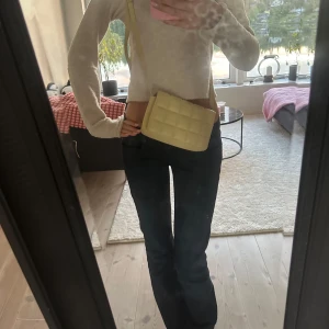 Gul axelväska med rutmönster - Säljer en snygg axelväska i ljusgul färg med quiltat rutmönster. Väskan har en rektangulär form och justerbar axelrem, perfekt för att bära över axeln. Materialet ser ut att vara syntet och den har en modern vibe som lyfter din outfit.🥹💛