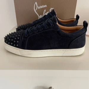 Christian Louboutin - ‼️Intresskoll‼️lägg bud‼️navy sneakers från Christian Louboutin med coola navy nitar på tån och klassisk röd sula. Skorna har snörning, rund tå och vit platt sula. Materialet är mocka och insidan är lyxigt läder. Medföljer originalkartong, dustbag och äkthetsbevis.