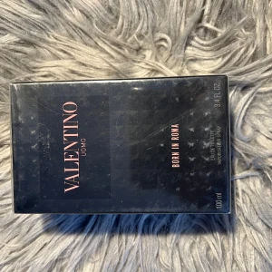 Valentino Uomo Born In Roma EdT 100ml - Valentino Uomo Born In Roma Eau de Toilette 100 ml. Snygg svart kartong med rosa detaljer och stilren design. Parfymen är för honom och kommer i en lyxig förpackning som känns exklusiv och modern. Perfekt för dig som gillar ikoniska dofter med italiensk känsla.
