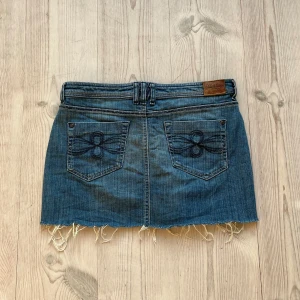 Blå lågmidjad jeanskjol  - Lågmidjad jeanskjol från Tom Tailor som jag har gjort om från en längre kjol. Fint skick. Tvärs över midjan är det 41 cm och längs med sidan är det 33 cm. Använd gärna köp nu!