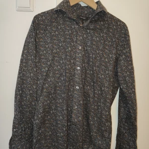 Blommig skjorta från Matinique, S - Snygg skjorta från Matinique i storlek S med småblommigt mönster i grått, beige och brunt. Skjortan har klassisk krage, knäppning framtill och långa ärmar. 