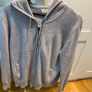 Sayless kashmir zip hoodie - En grå sayless kashmir hoodie med dragkedja och skönt material, passar perfekt till alla typer av tider, och även platser. Man kan ha den hemma, i skolan, eller på en fin middag. Hoodien passar bra på mig, och jag är 175 centimeter, men jag skulle söga att den kan sitta riktigt fint mellan 170-185 centimeter. Den är nopprig, vilket går att fixa med kashmir kam, därav priset. Säljer för att den inte riktigt passar min stil, inga andra defekter. Pris ej diskuterbart