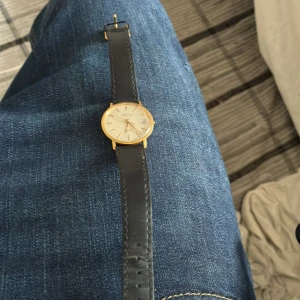 Certina guldquartzklocka med svart läderband - Stilren Certina quartzklocka med rund guldfärgad boett och vit urtavla. Klockan har datumvisning och ett klassiskt svart läderband. Perfekt för dig som gillar tidlös och elegant design med en touch av vintage.