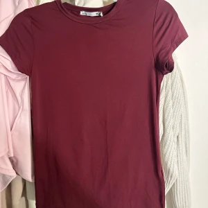 Vinröd t-shirt från 157 - Vinröd Cleo-topp från Lager 157 i nyskick, endast testad en gång och prislappen sitter kvar. Tajt modell i sportigt stretchmaterial som formar sig efter kroppen. Storlek L men stretchig, passar från XS till XL beroende på önskad passform. ‼️‼️Prissänkning vid direktköp ‼️‼️